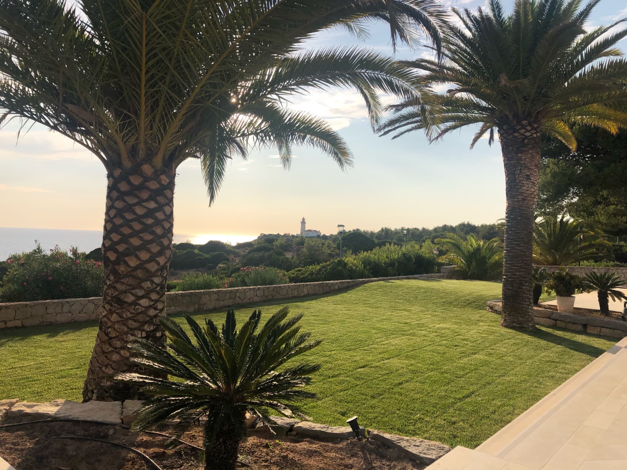 Jardineiro a aparar relva e bordaduras em jardim privado no Algarve